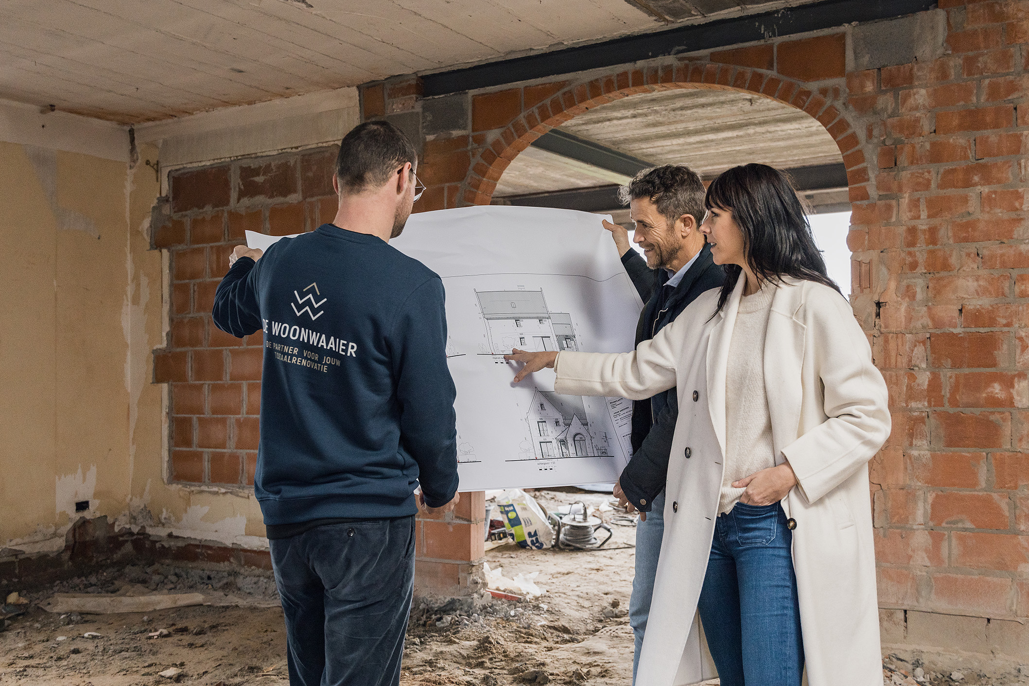 Een koppel kijk samen met een specialist op de tekening van hun ruwbouwwoning waar een poutrel geplaatst kan worden.